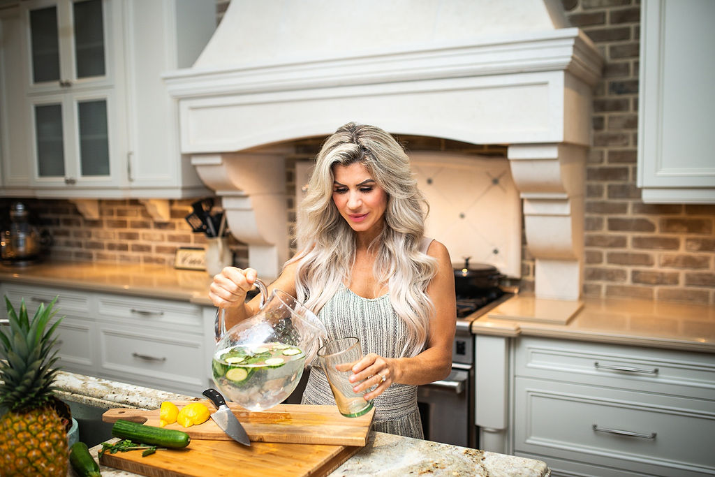 Mandy pouring fresh cucumber water in a bright modern kitchen
