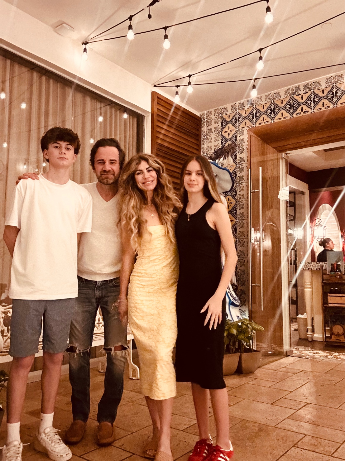 Mandy with her husband, son, and daughter under string lights